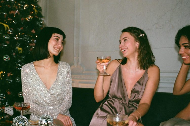 three women laughing beside christmas tree