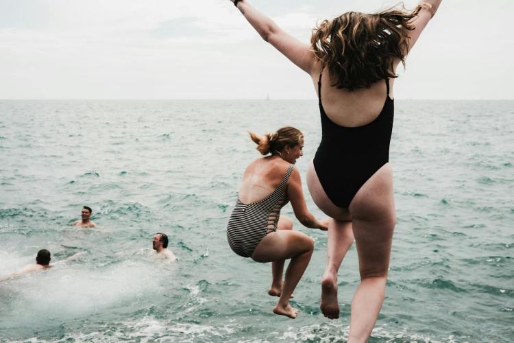 women jumping to sea
