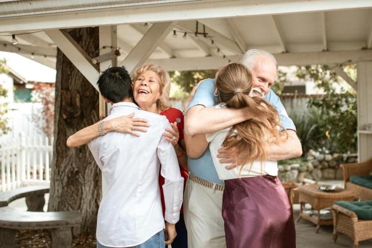 an elderly couple embracing their son and daughter