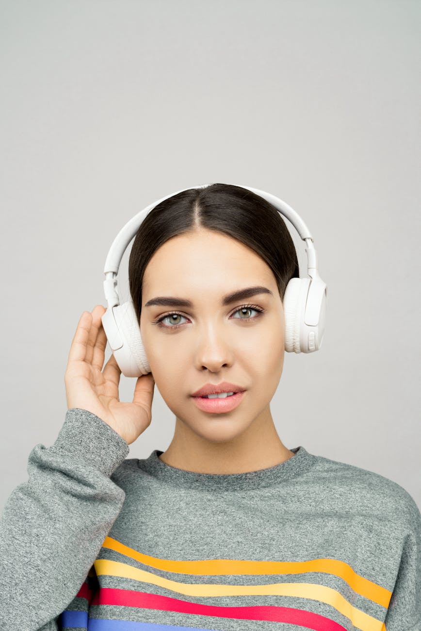 woman in gray sweater wearing white headphones