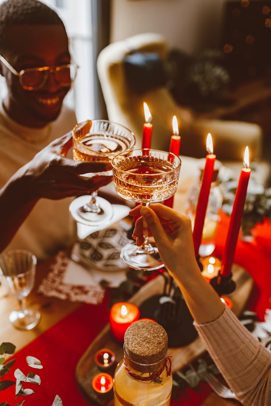 man and woman making a toast with champagne and red candles on table