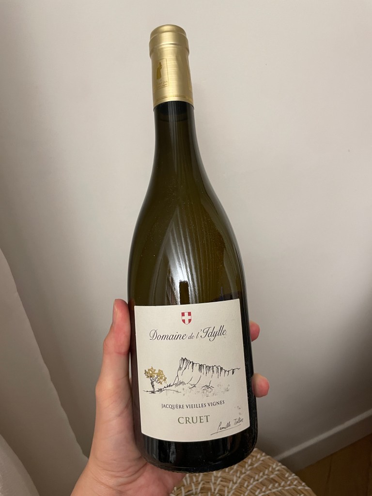 Bouteille de vin blanc 'Domaine de l'Idylle', étiquetée 'Jacquère Vieilles Vignes', Cruet, tenue dans une main.