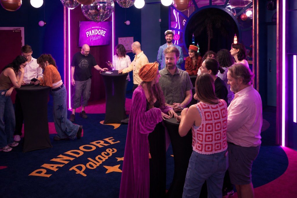 A vibrant social gathering inside Pandore Palace, featuring a diverse group of people interacting at standing tables, with neon lights and disco balls in the background.