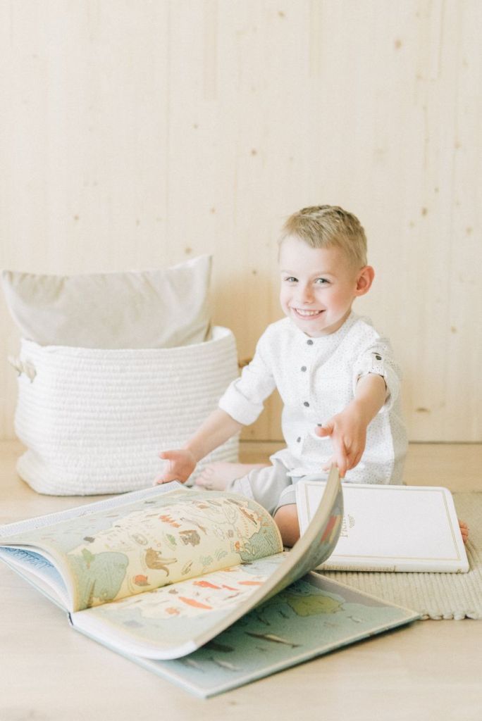 smiling boy sitting while reading an educational book